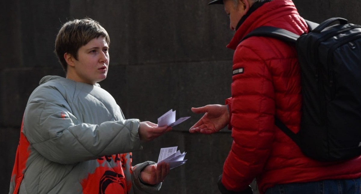 Лена Патяева вручает прохожему в Санкт-Петербурге листовку об исчезновении Седы Сулеймановой. 8 марта 2024 года. Фото: Sota https://t.me/sotaproject/76335