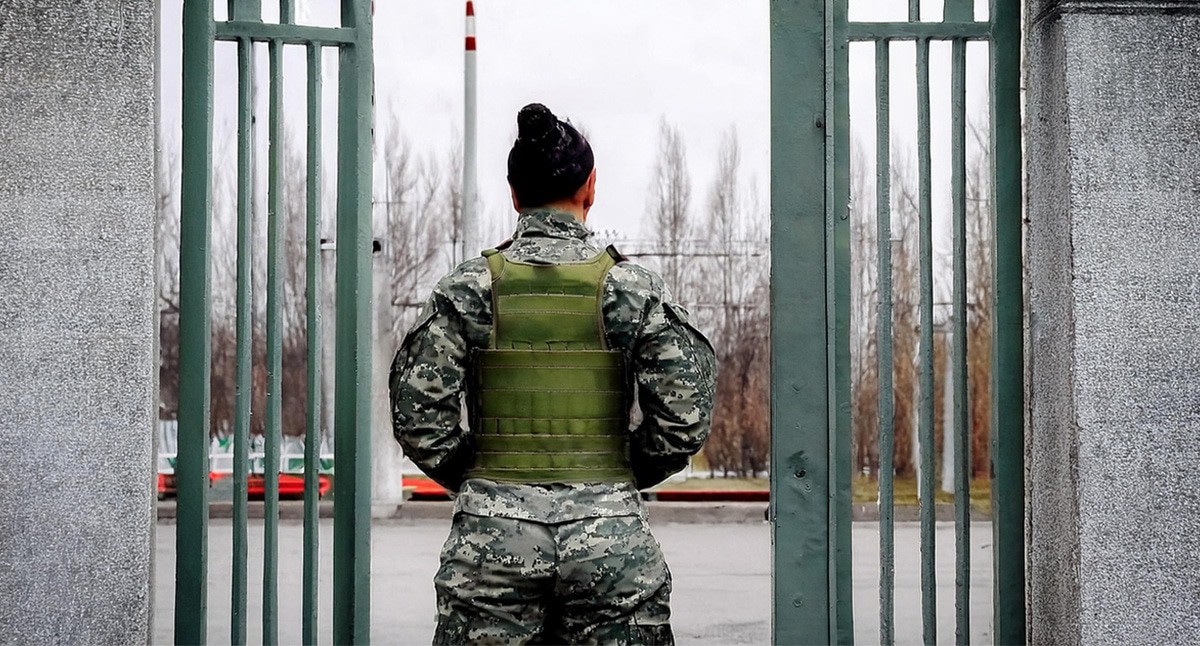 Военный в воротах воинской части. Иллюстрация создана «Кавказским узлом» с помощью ИИ в программе Photoshop